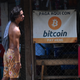 A man standing outside a shop in El Salvador that accepts bitcoin.